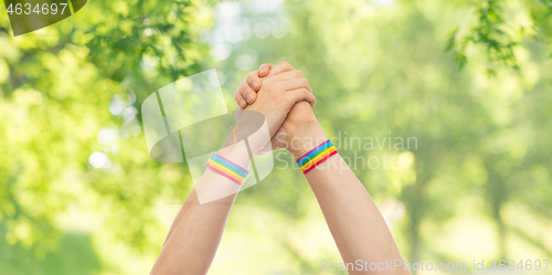 Image of hands with gay pride wristbands in winning gesture