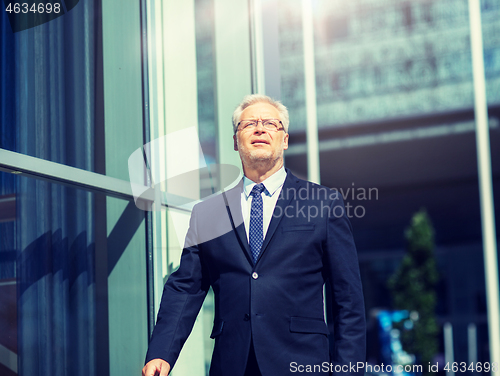 Image of senior businessman walking along city street