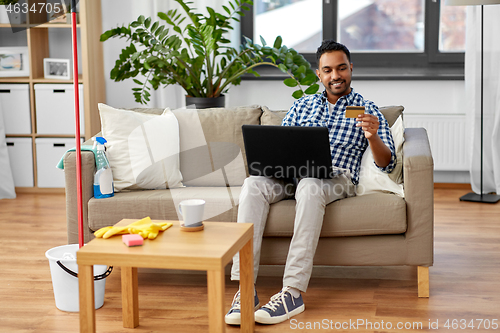 Image of man with laptop shopping online after cleaning