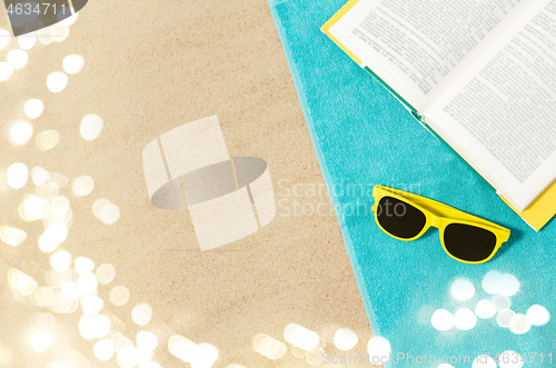 Image of sunglasses and book on beach towel on sand