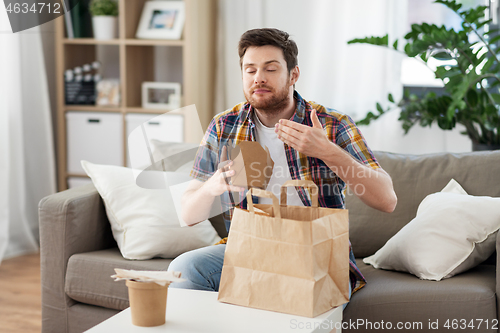 Image of smiling man unpacking takeaway food at home