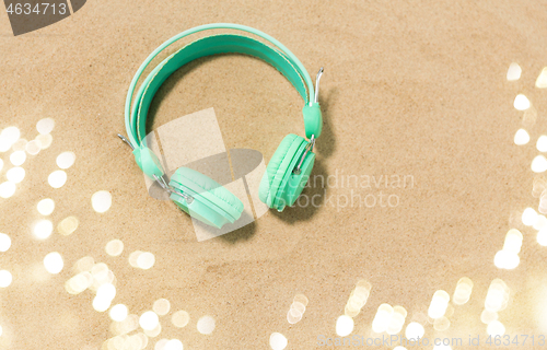 Image of earphones on summer beach sand