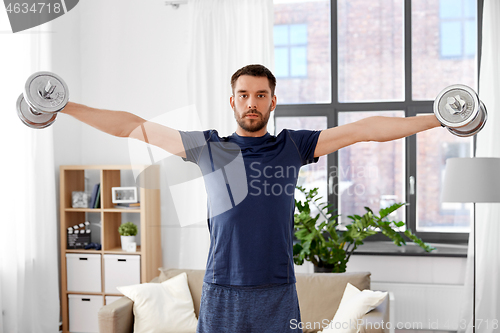 Image of smiling man exercising with dumbbells at home