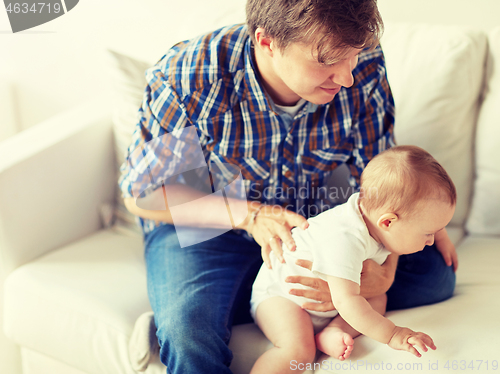 Image of happy young father with little baby at home