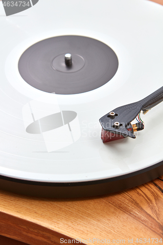 Image of Vintage record player with vinil disc on a wooden table.