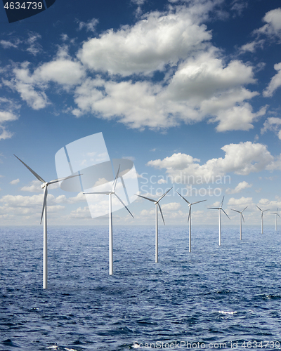 Image of Row from wind turbines in an open sea water on a background of cloudy sky.