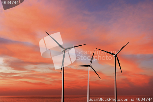 Image of Wind turbines as alternative renewable energy on a background sunset sky.