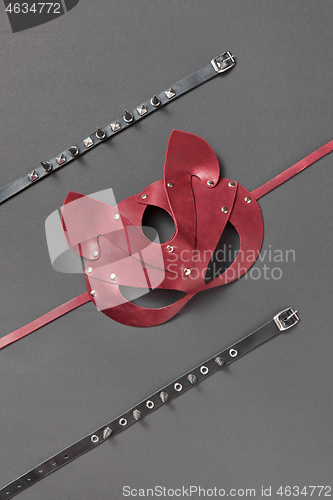 Image of Red leather cat BDSM mask and stud collars on a black background.