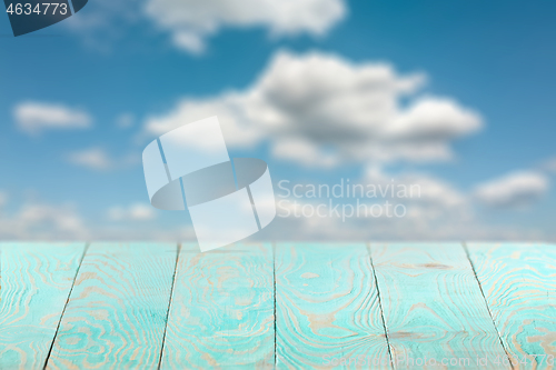 Image of Empty wooden backdrop of blue color on a background of blurred sky.