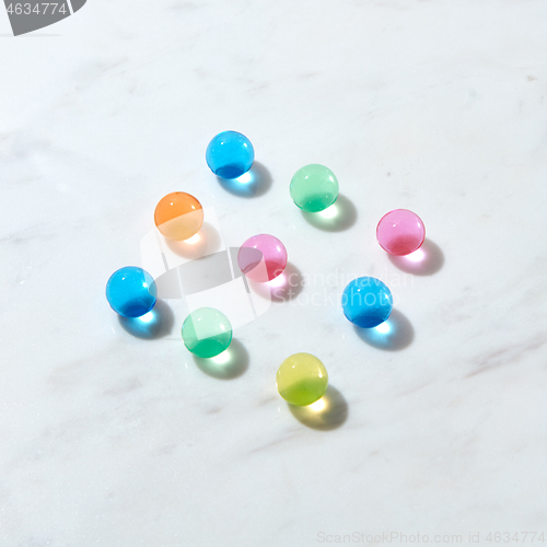 Image of Diagonal pattern from hydrogel color balls on a grey marble table.