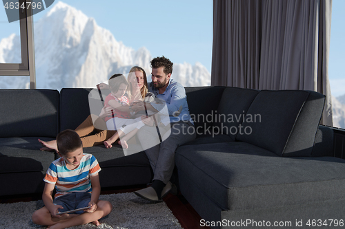 Image of happy young couple spending time with kids at home