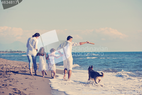 Image of happy family playing with dog on beach