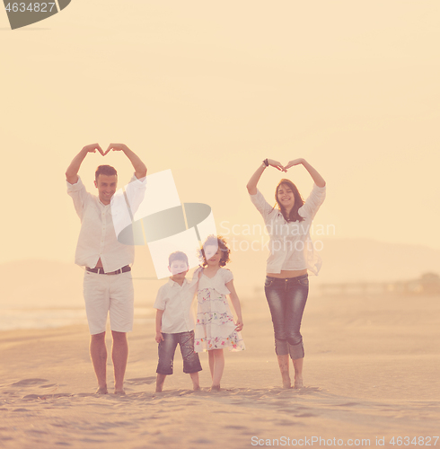 Image of happy young family have fun on beach at sunset