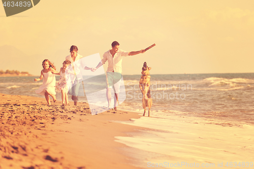 Image of happy family playing with dog on beach