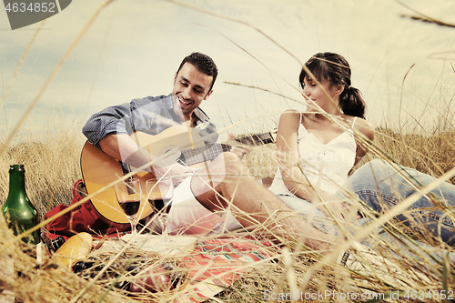 Image of happy couple enjoying countryside picnic in long grass