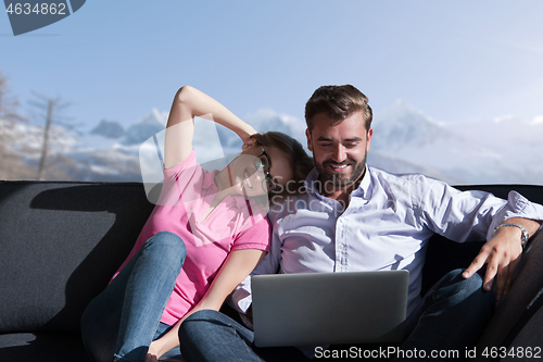 Image of couple relaxing at  home using laptop computers