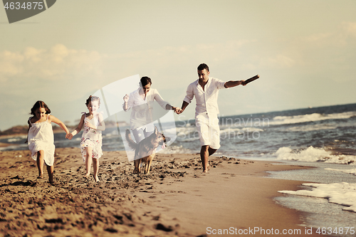 Image of happy family playing with dog on beach