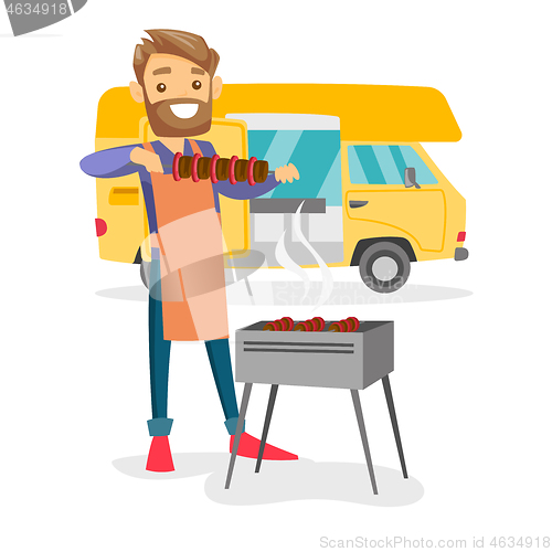 Image of Young man barbecuing meat in front of camper van.