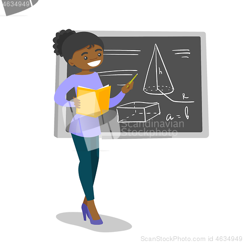 Image of African teacher standing in front of blackboard.