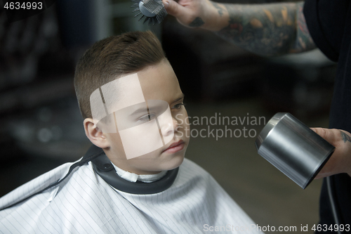 Image of Children hairdresser cutting little boy against a dark background.