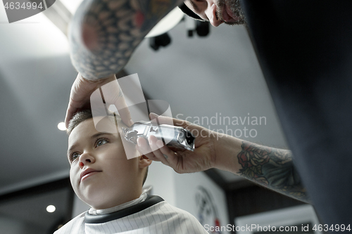 Image of Children hairdresser cutting little boy against a dark background.