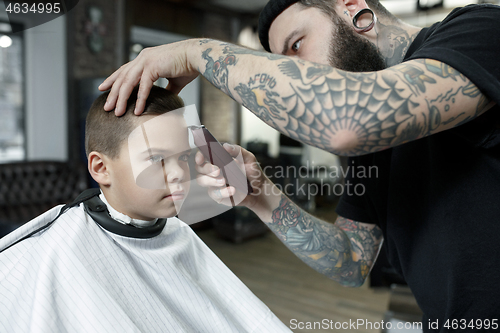 Image of Children hairdresser cutting little boy against a dark background.