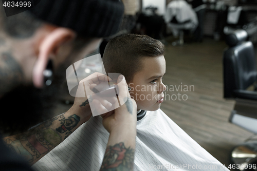 Image of Children hairdresser cutting little boy against a dark background.