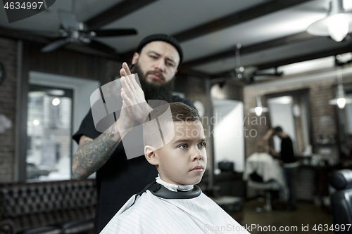 Image of Children hairdresser cutting little boy against a dark background.