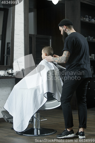 Image of Children hairdresser cutting little boy against a dark background.