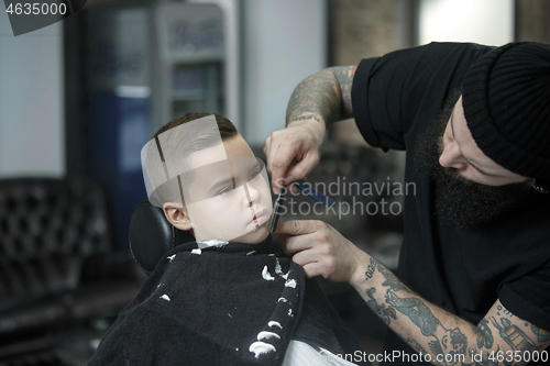 Image of Children hairdresser cutting little boy against a dark background.