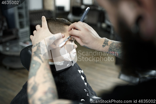 Image of Children hairdresser cutting little boy against a dark background.