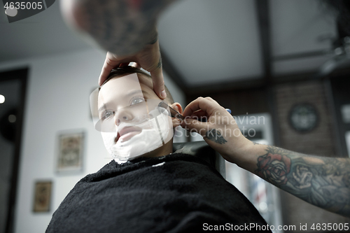 Image of Children hairdresser cutting little boy against a dark background.