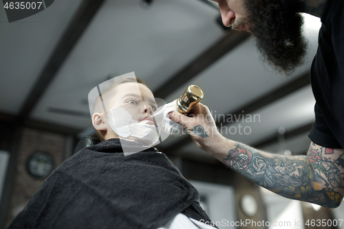 Image of Children hairdresser cutting little boy against a dark background.