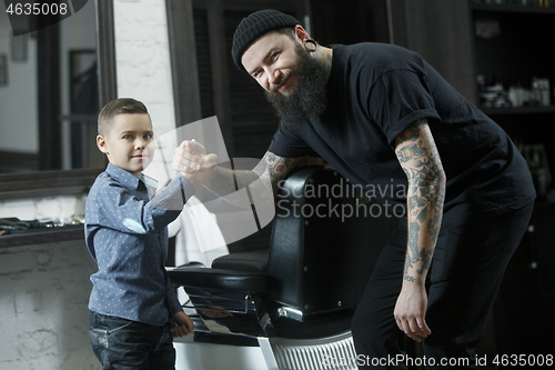 Image of Children hairdresser cutting little boy against a dark background.