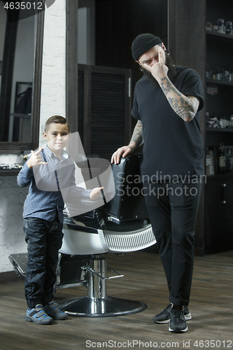 Image of Children hairdresser cutting little boy against a dark background.