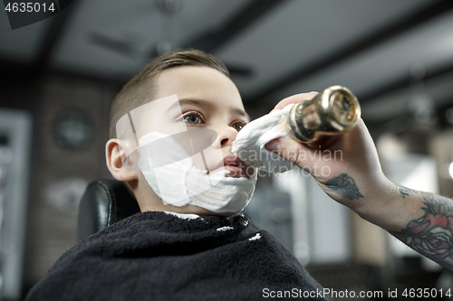 Image of Children hairdresser cutting little boy against a dark background.