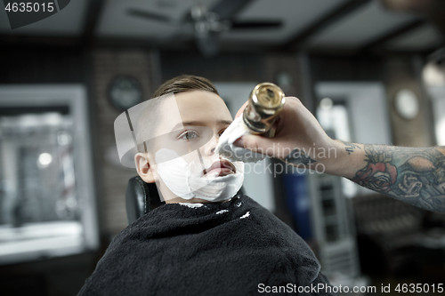 Image of Children hairdresser cutting little boy against a dark background.