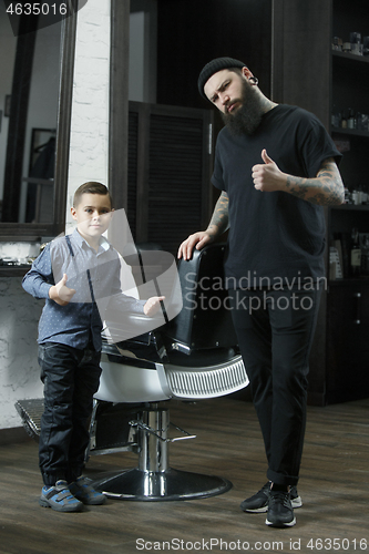 Image of Children hairdresser cutting little boy against a dark background.