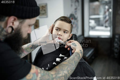 Image of Children hairdresser cutting little boy against a dark background.