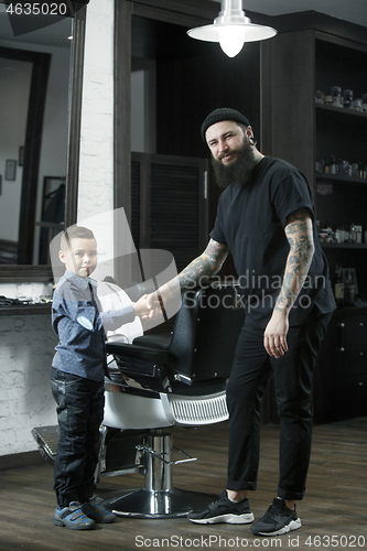 Image of Children hairdresser cutting little boy against a dark background.