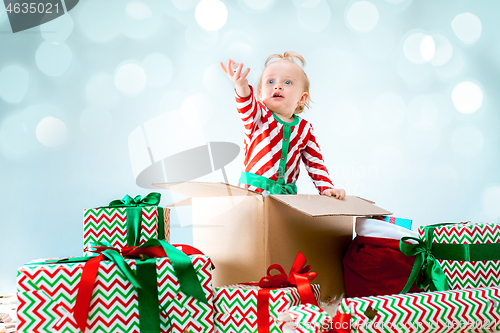 Image of Cute baby girl 1 year old sitting at box over Christmas background. Holiday season.