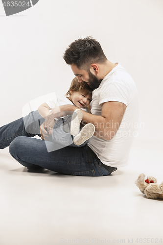 Image of happy family with kid sitting together and smiling at camera isolated on white