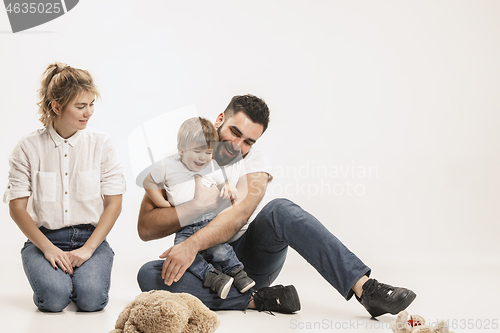 Image of happy family with kid sitting together and smiling at camera isolated on white