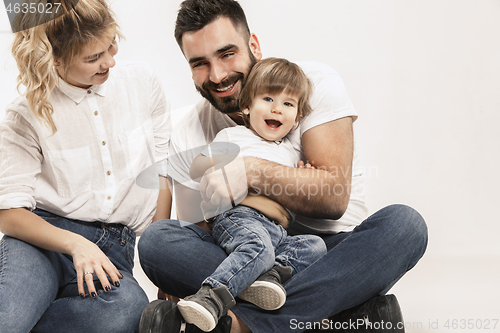 Image of happy family with kid sitting together and smiling at camera isolated on white