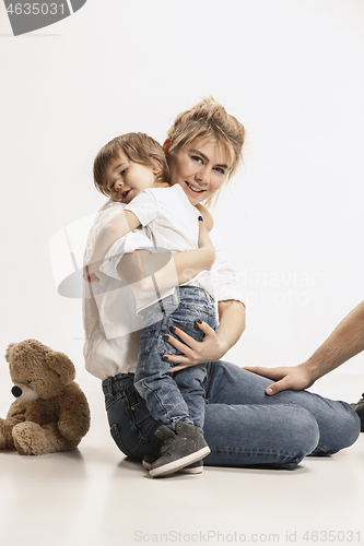 Image of happy family with kid sitting together and smiling at camera isolated on white