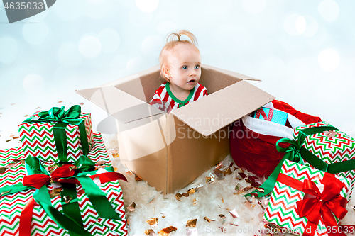 Image of Cute baby girl 1 year old sitting at box over Christmas background. Holiday season.