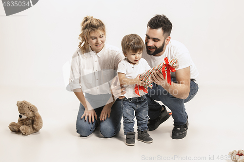 Image of happy family with kid sitting together and smiling at camera isolated on white