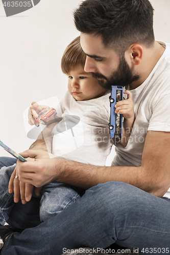 Image of happy family with kid sitting together and smiling at camera isolated on white