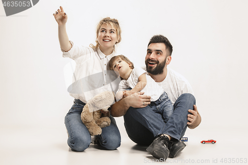 Image of happy family with kid sitting together and smiling at camera isolated on white