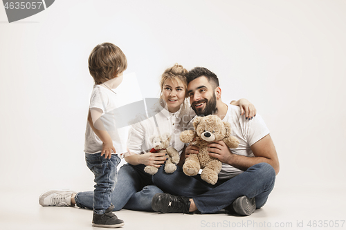 Image of happy family with kid sitting together and smiling at camera isolated on white